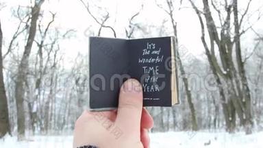 这`一年中最美妙的时刻。 手拿着一本背景文字的书-冬季公园
